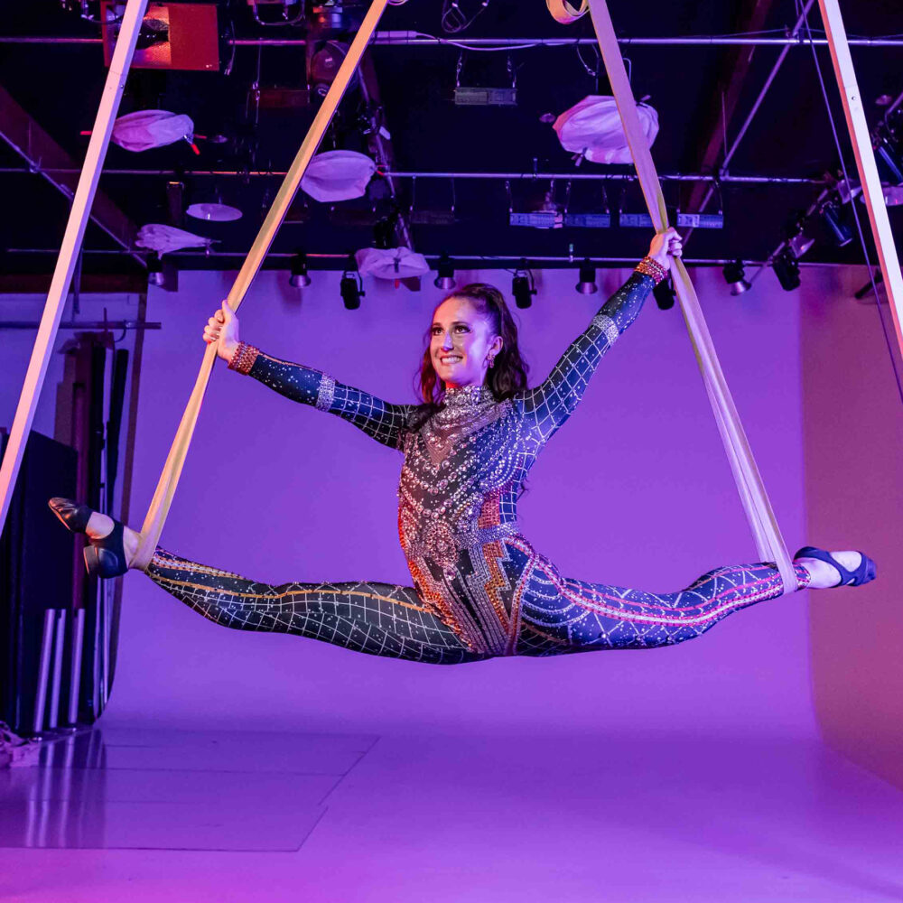 arial artist Skylar hanging from silks attached to the ceiling